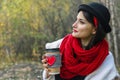 Young woman in a black hat drinks coffee from cozy cup on the nature. Bright smile and good mood Royalty Free Stock Photo