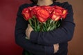 woman in a black jacket embraces a bouquet of large roses