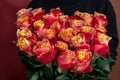 woman in a black jacket embraces a bouquet of large roses