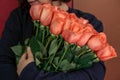 woman in a black jacket embraces a bouquet of large roses