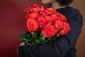 woman in a black jacket embraces a bouquet of large roses