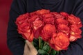 woman in a black jacket embraces a bouquet of large roses