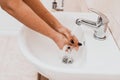 Young woman with black manicure washing hands with soap over sink in bathroom, close up Royalty Free Stock Photo