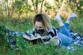 Young woman with black protective mask reading a book in the park