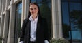 Young woman in a black suit looking to camera outside on street. Businesswoman portrait near office building. Royalty Free Stock Photo