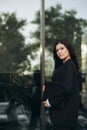 Young woman in a black suit looking to camera outside on street. Businesswoman portrait near office building. Royalty Free Stock Photo