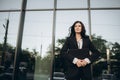 Young woman in a black suit looking to camera outside on street. Businesswoman portrait near office building. Royalty Free Stock Photo