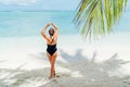 Young woman in black swimsuit entering shallow warm Indian ocean water on white sandy beach on Mauritius coast enjoying wide ocean Royalty Free Stock Photo