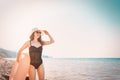 A young woman in a black swimsuit and hat holding an orange swimming circle and looking into the distance.The sea in the Royalty Free Stock Photo