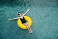 Happy woman in a pool swimming on an inflatable buoy, looking up at camera Royalty Free Stock Photo
