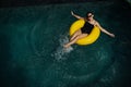 Happy woman in a pool swimming on an inflatable buoy and smiling Royalty Free Stock Photo
