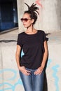 Young woman in black t shirt and jeans with dreadlocks hairstyle sunglasses and outdoor in city spring summer day