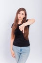 Young woman in black t-shirt showing thumb down gesture isolated on white background Royalty Free Stock Photo