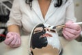 young woman with black and white clay cosmetic mask on half face lying a bad on spa salon Royalty Free Stock Photo