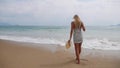 Young woman in black and white dresses walking alone on a tropical beach and watching the storm on the sea. Travel