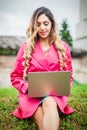 Young woman blogger influencer works on laptop on meadow in park Royalty Free Stock Photo