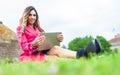 Young woman blogger influencer works on laptop on meadow in park Royalty Free Stock Photo