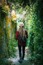 A young woman with blond dreadlocks, back view, goes through the greens.