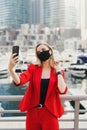 Young woman with blond hair wearing red suit and protective face mask Royalty Free Stock Photo