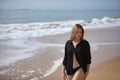 Young woman, blonde and beautiful, with a bikini and black shirt walking on the beach, relaxed, quiet, peaceful, calm. Concept of