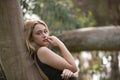 Young woman, blonde and beautiful, with a black dress, leaning on the trunk of a tree, in the middle of nature, pure and virginal Royalty Free Stock Photo