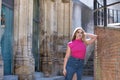 Young woman, blonde, green eyes, wearing pink t-shirt and denim skirt, looking at camera, pensive and calm, leaning against a Royalty Free Stock Photo