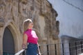 Young woman, blonde, green eyes, wearing pink t-shirt and denim skirt, looking at the sky, praying and begging, leaning on a Royalty Free Stock Photo