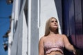 Young woman, blonde, green eyes, wearing pink top and jeans, looking at the sky, leaning against the frame of a white Andalusian Royalty Free Stock Photo