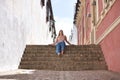 Young woman, blonde, green eyes, wearing pink top and jeans, sitting on a staircase, looking at the camera, relaxed and calm. Royalty Free Stock Photo