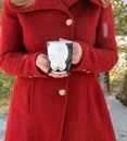 Young woman with blonde hair in red coat holding cute holiday mug