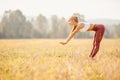 Young woman blonde in red pants and white T-shirt performs warm before running in park Royalty Free Stock Photo