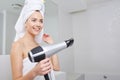 Young woman blow drying hair in bathroom