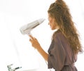 Young woman blow drying hair in bathroom Royalty Free Stock Photo