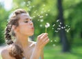 Young woman blowing away dandelion Royalty Free Stock Photo
