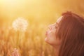 Young woman blowing dandelion in autumn landscape at sunset Royalty Free Stock Photo