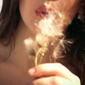 Young woman blowing dandelion flower outdoor summer day closeup focus on lips Royalty Free Stock Photo