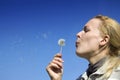 Young woman blowing dandelion seeds