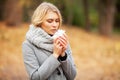 Young woman blowing her nose on the park. Woman portrait outdoor sneezing because cold and flu