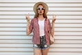 Young woman blowing red lips sending sweet air kiss showing peace hand sign wearing summer round straw hat, checkered shirt Royalty Free Stock Photo