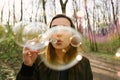 Young woman blowing soap bubbles in the woods Royalty Free Stock Photo