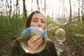 Young woman blowing soap bubbles in the woods Royalty Free Stock Photo