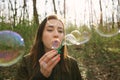 Young woman blowing soap bubbles in the woods Royalty Free Stock Photo