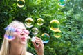 Young woman blows soap bubbles in the street. Close-up portrait. Happiness and positive emotions concept. Soft focus Royalty Free Stock Photo