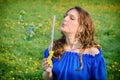 Young woman in a blue dress blows soap bubbles on a background of a field with dandelions Royalty Free Stock Photo