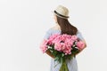 Young woman in blue dress, hat holding bouquet of beautiful pink peonies flowers behind her back isolated on white Royalty Free Stock Photo