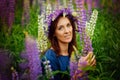 A young woman in a blue dress is picking tall pink-lilac lupin flowers in a meadow. Portrait in the open air Royalty Free Stock Photo