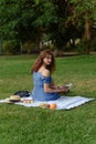 Young woman in blue dress reads a book at a picnic in the park .Cozy picnic of summer day