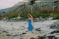 Young woman in blue dress walking on white sand, fish dryers on background Royalty Free Stock Photo