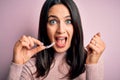 Young woman with blue eyes holding clear aligner standing over pink background screaming proud and celebrating victory and success Royalty Free Stock Photo