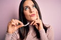 Young woman with blue eyes holding clear aligner standing over pink background serious face thinking about question, very confused Royalty Free Stock Photo